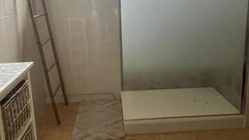 Ein Badezimmer mit Dusche, einer Leiter und Fliesenboden.