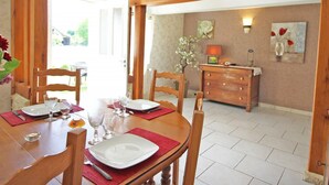 Comedor con una mesa de madera preparada para cuatro personas, sillas y un aparador de madera con una lámpara.