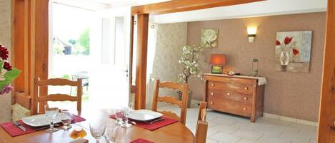 A dining area with a wooden table set for four, chairs, and a wooden cabinet with a lamp.