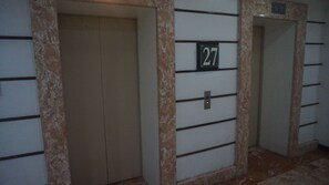 Um corredor com duas portas, uma delas identificada com o número 27.
