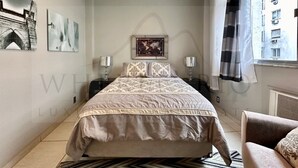 A bedroom with a bed, two bedside tables, a window with curtains, and artwork on the walls. - Come relax and enjoy Rio in Modern Ipanema Luxury! (Rio de Janeiro)