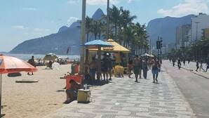 A beachside walkway with umbrellas, people, and buildings in the background. - Come relax and enjoy Rio in Modern Ipanema Luxury! (Rio de Janeiro)
