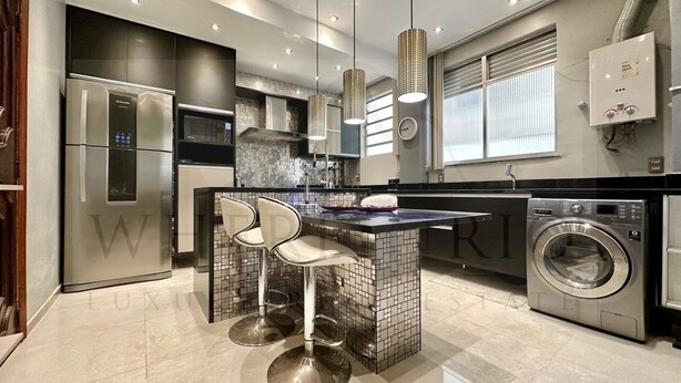 A modern kitchen with a built-in island, stainless steel appliances, and a washing machine. - Come relax and enjoy Rio in Modern Ipanema Luxury! (Rio de Janeiro)