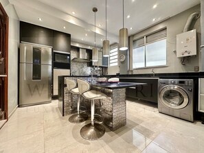 A modern kitchen with a built-in island, stainless steel appliances, and a washing machine. - Come relax and enjoy Rio in Modern Ipanema Luxury! (Rio de Janeiro)