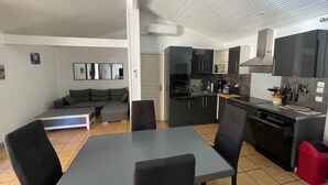 A compact living space with a dining area, kitchenette, and a gray sofa. - Near SOULAC/mer, air-conditioned house with heated indoor pool sleeps 4 (Grayan-et-l'Hôpital)
