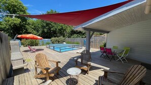 A wooden deck with outdoor furniture, a pool, and a covered area with chairs and a table. - Near SOULAC/mer, air-conditioned house with heated indoor pool sleeps 4 (Grayan-et-l'Hôpital)