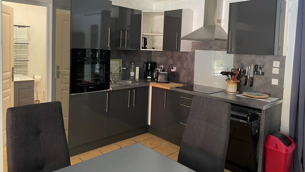 A modern kitchen with dark cabinetry, a built-in oven, a coffee maker, and a dishwasher. - Near SOULAC/mer, air-conditioned house with heated indoor pool sleeps 4 (Grayan-et-l'Hôpital)