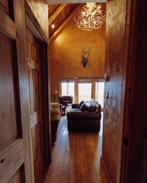 A wooden interior with a mounted deer head, a fireplace, and a leather sofa.
