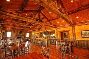 A rustic log cabin interior with a bar area, wooden furniture, and a stone fireplace. - Cozy Two Bedroom Cabin on Private Montana Dude Ranch - Bear's Den (Belt)