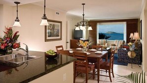 A modern kitchen with a central island, a dining area with a view, and a living room with a view.
