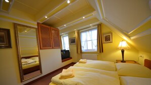 Une chambre d’hôtel avec deux lits, un grand miroir, une fenêtre avec des rideaux, une lampe et un radiateur.