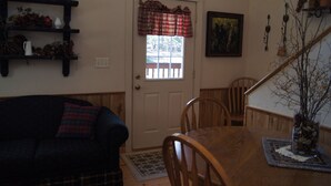 A dining room with a wooden table, chairs, a sofa, a door with a window, and a staircase. - Elk Haven Vacation Cabins, Custer SD, Elk Haven Vacation Cabins, Custer SD (Custer)