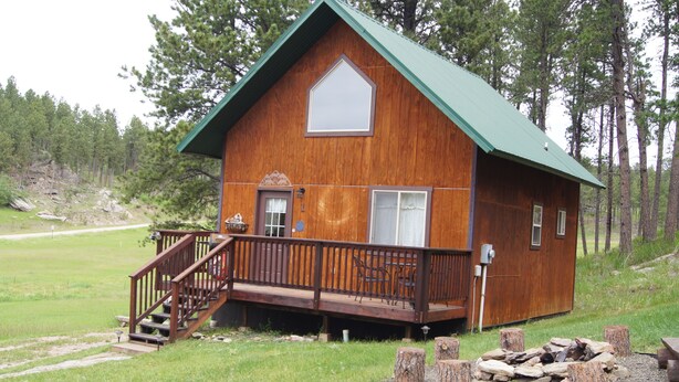 A wooden cabin with a green roof, a front porch with a staircase, and a fire pit. - Elk Haven Vacation Cabins, Custer SD, Elk Haven Vacation Cabins, Custer SD (Custer)