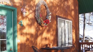 A wooden cabin with a green door, a number '4' on the wall, a table with chairs, and a window. - Elk Haven Vacation Cabins, Custer SD, Elk Haven Vacation Cabins, Custer SD (Custer)