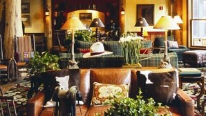 A cozy, rustic interior with wooden beams, a central fireplace, and a variety of seating arrangements including sofas and chairs. - Teton Club - 3 Bedroom/3 Bath, Ski in/Ski out, 2 free lift tickets (Teton Village)