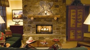 A cozy living room with a stone fireplace, a green sofa, a wooden coffee table, and a decorative hat. - Teton Club - 3 Bedroom/3 Bath, Ski in/Ski out, 2 free lift tickets (Teton Village)