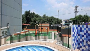 A swimming pool with a tiled border, a brick play structure, and a fenced area. - APARTMENT IN NORTH PRADOS (Cali)