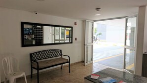 A reception area with a bench, a chair, a counter with brochures, and a door leading outside. - APARTMENT IN NORTH PRADOS (Cali)