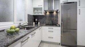 A modern kitchen with white cabinets, granite countertops, a stainless steel refrigerator, and a coffee maker. - Always Easy I Ático Plaza (San Sebastián/Donostia)