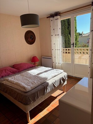 Un dormitorio con cama, lámpara, calefactor y vistas al exterior.