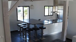Una cocina moderna con una isla central, taburetes de bar y una mesa de comedor.