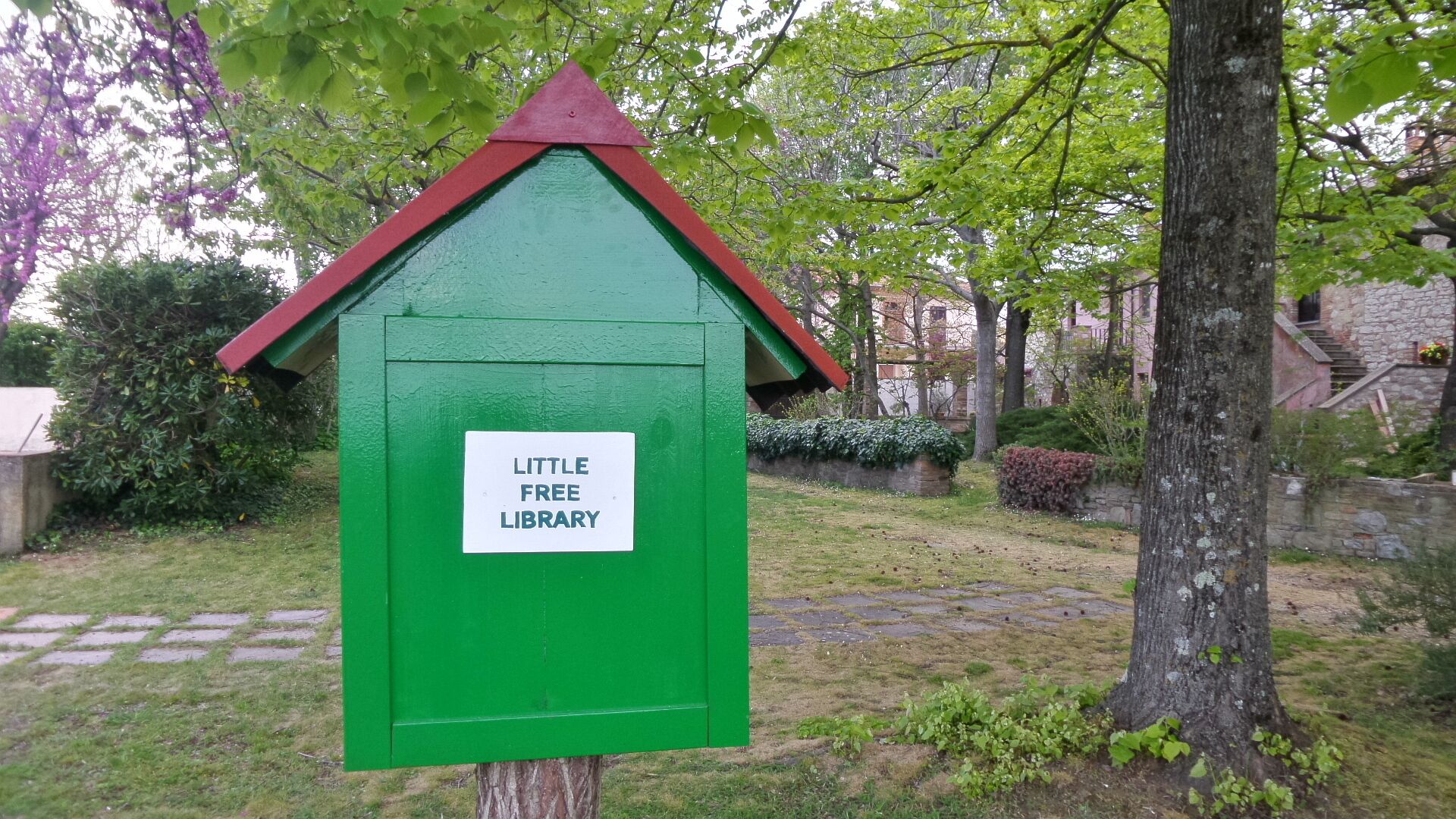 Ein grünes Schild mit einer Bibliothekssymbol auf einem Baum.