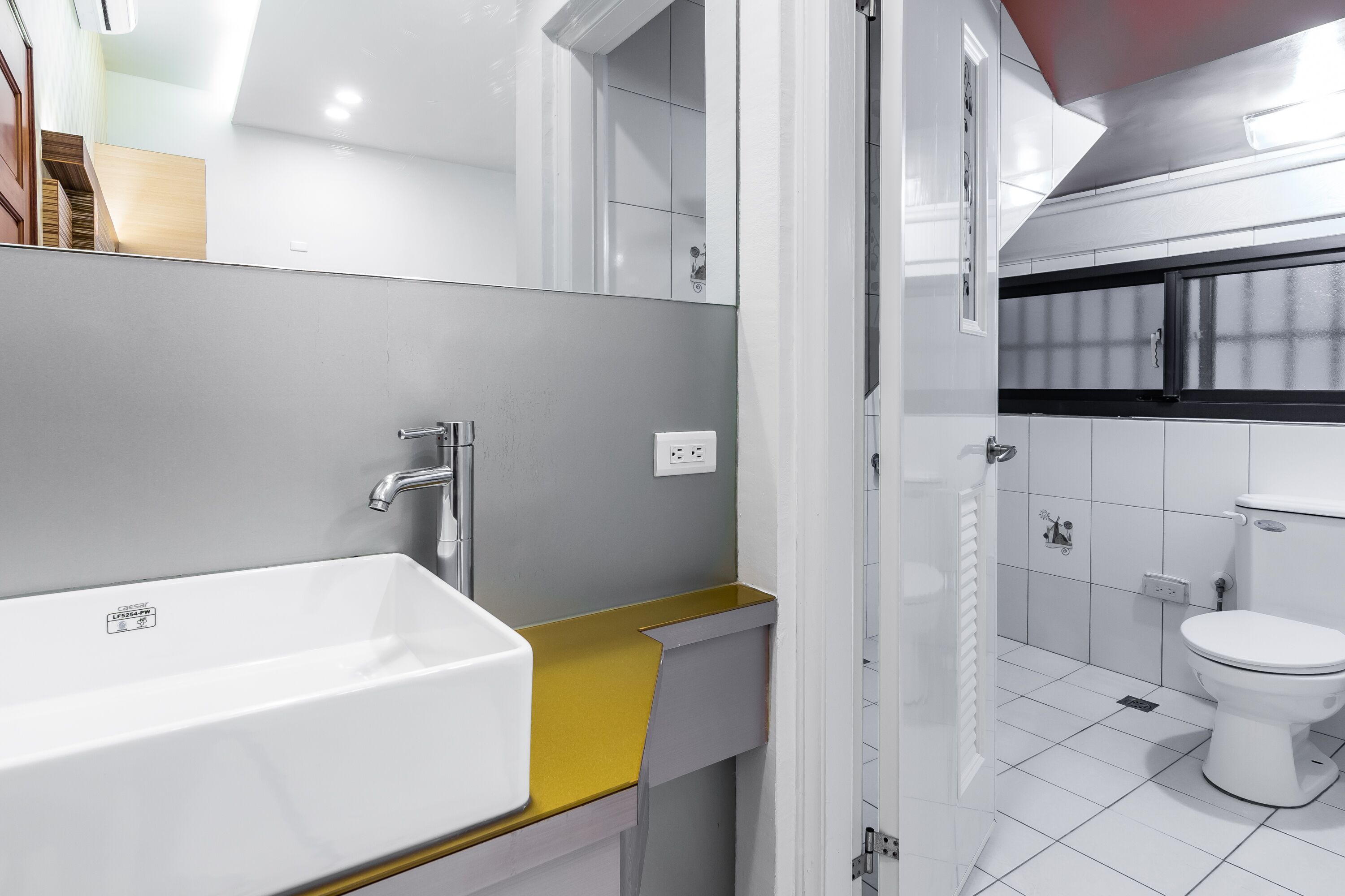 A modern bathroom with a white sink, yellow countertop, and a white toilet.