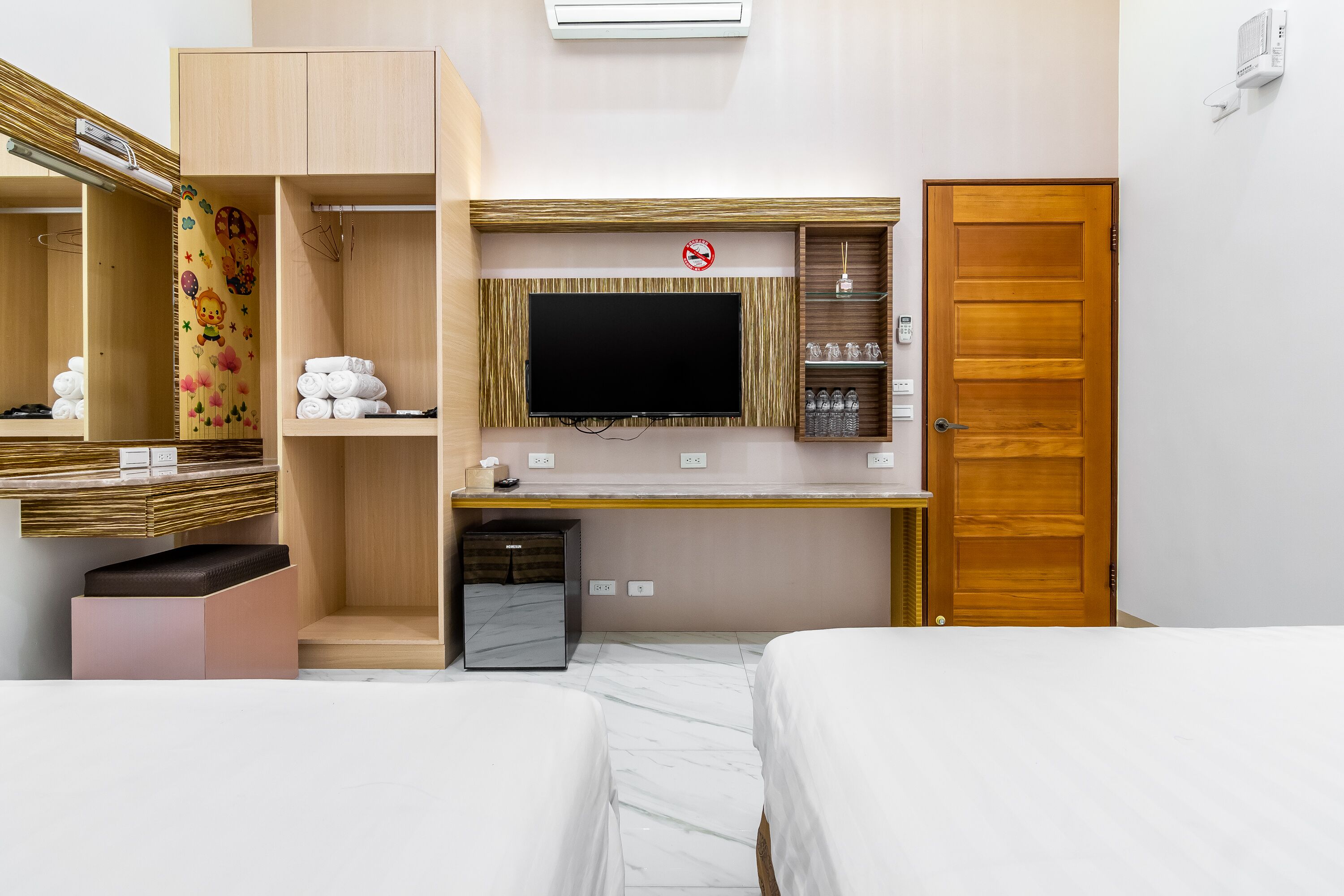 A hotel room with a bed, a desk with a flat-screen TV, a wardrobe, and a bathroom.