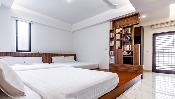 Una habitación de hotel moderna con dos camas, una estantería de madera y un ventanal grande.