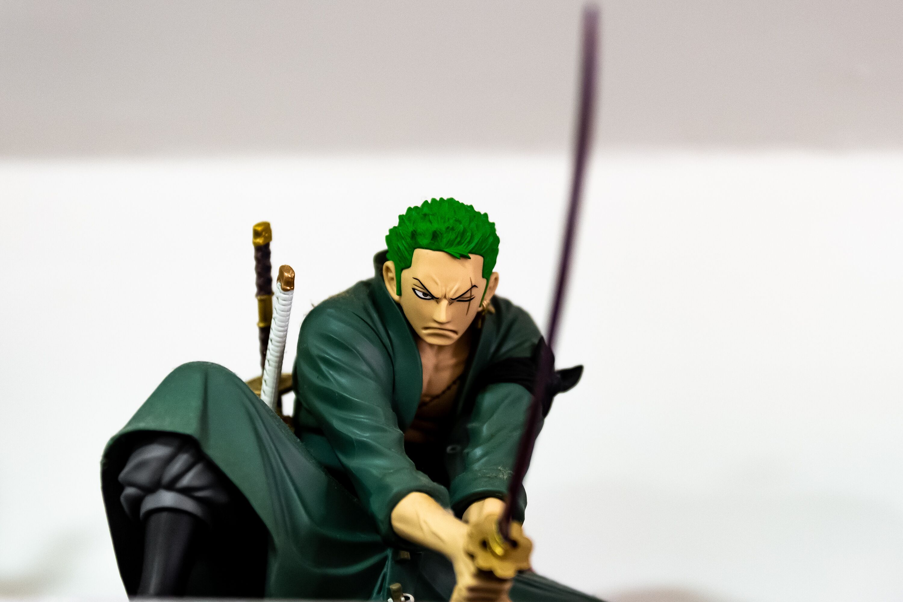 Una figurita de un personaje de cabello verde, vestido con un traje verde, sosteniendo una espada.