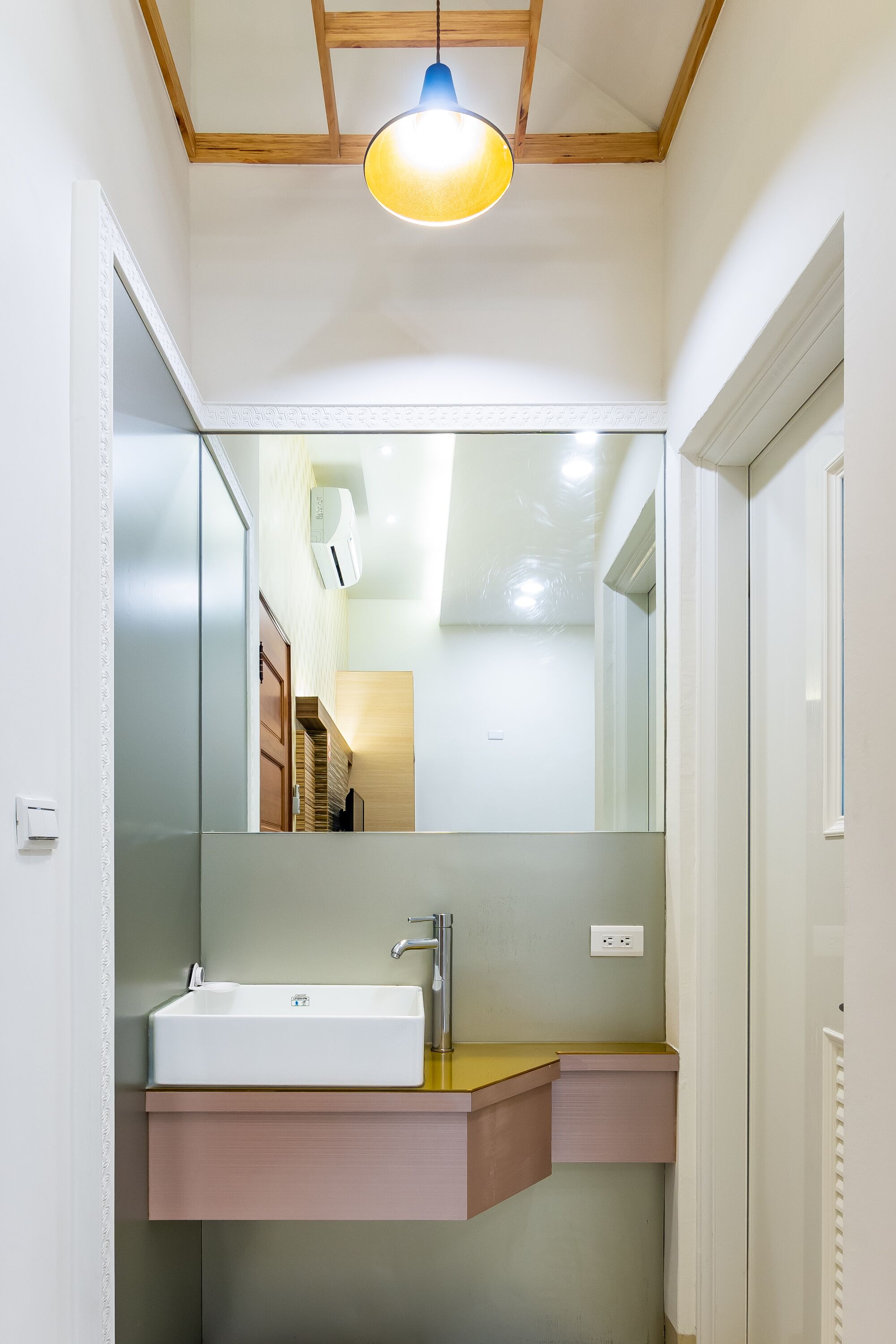 Un baño con un espejo grande, un lavabo y una lámpara.