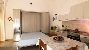 A compact kitchen with a dining table, a sink, and a small refrigerator. - Fittasi Studio in Ostuni (BR) (Ostuni)