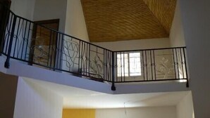 Un intérieur à plusieurs niveaux, doté d’une balustrade de balcon, d’un plafond en bois et d’une fenêtre.
