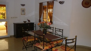 Un coin repas avec une table et des chaises, un vase avec des fleurs, une fenêtre avec des rideaux et un meuble.