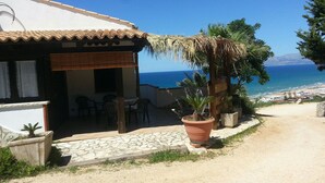 Una propiedad costera con patio, mobiliario exterior y vistas al mar.