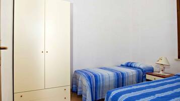 Ein Zimmer mit zwei Betten, einem Schrank und einem Nachttisch mit Lampe.