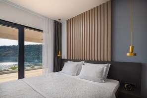 Une chambre moderne avec un grand lit, une vue sur l’extérieur et un mur décoratif unique en panneaux de bois.