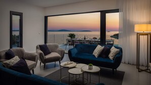 A modern living room with a view of the sea, featuring a sofa, armchairs, and a dining area. - Beachfront Villa Eleganza with Pool (Marina)