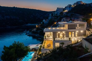 Une villa moderne dotée d’une piscine, de plusieurs balcons et offrant une vue sur la mer.