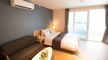 Una camera d'albergo con un letto, un divano, un comodino e una finestra con tende.
