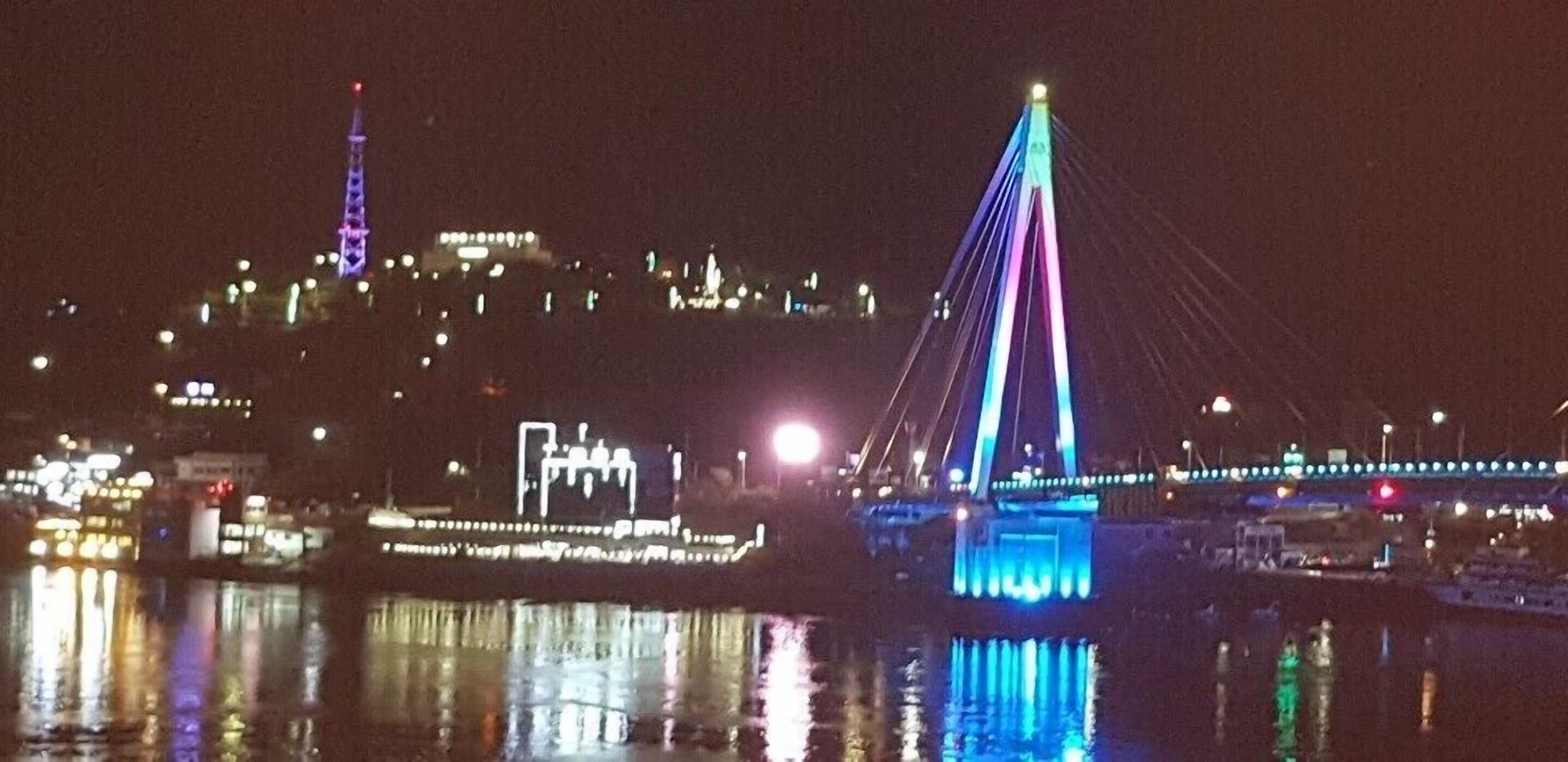 Een verlicht stadsbeeld bij nacht, met een heldere brug en een omlichtte toren.