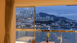 Una habitación con un ventanal grande que da a un paisaje urbano y una masa de agua.