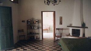 A room with a checkered floor, a bookshelf, a rocking chair, a fireplace, and a door leading to another room.