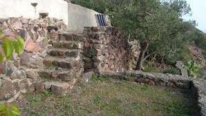 A stone staircase leading up to a building with a white exterior and a green window.