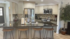 A modern kitchen with a central island, stainless steel appliances, and a potted plant.