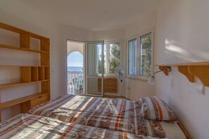 Ein Schlafzimmer mit einem Bett, Holzböden, einem Fenster und Blick aufs Meer.