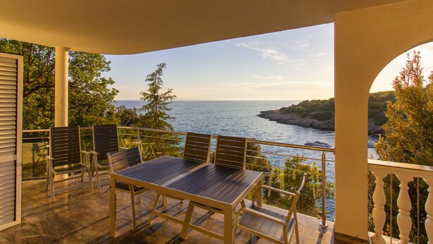 A balcony with a table and chairs overlooking a body of water and greenery. - Beach Apartment 1: private bathing area, sandy beach, WiFi, ideal for families (Novalja)