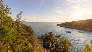 A coastal landscape with a clear sky, trees, and boats on the water. - Beach Apartment 1: private bathing area, sandy beach, WiFi, ideal for families (Novalja)