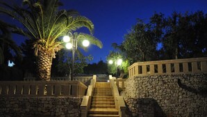 A stone staircase leading up to a building entrance, surrounded by palm trees and street lamps. - Cappero Pool House by Galatea Holiday Homes (Gagliano del Capo)