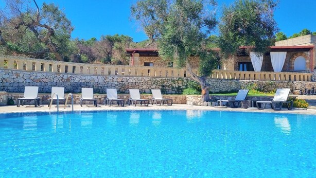 A clear blue pool with lounge chairs and a stone wall. - Cappero Pool House by Galatea Holiday Homes (Gagliano del Capo)
